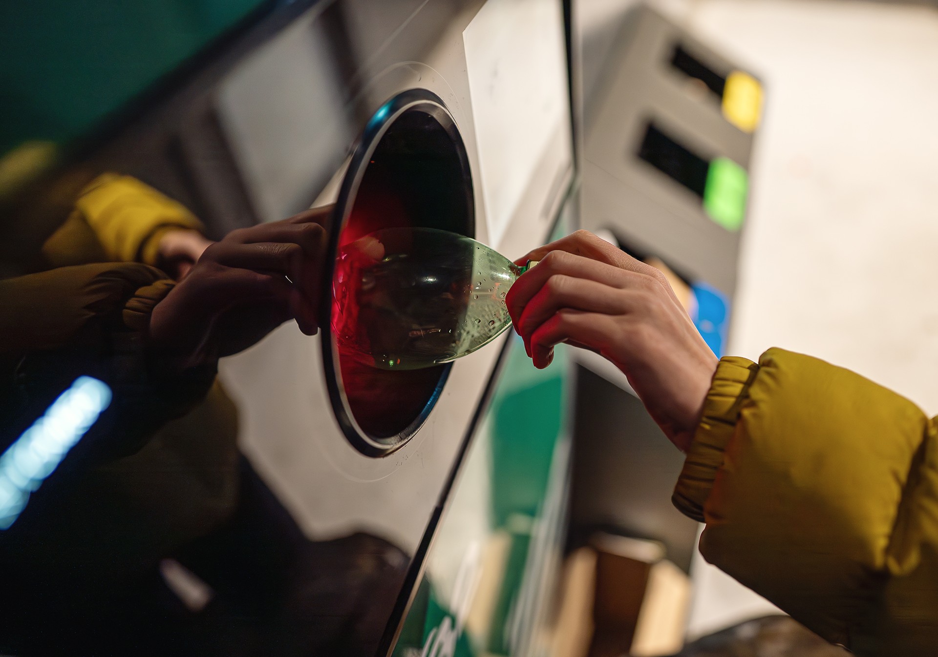 Woman puts bottle in automatic bottle recycling machine. Reverse vending recycling machine.